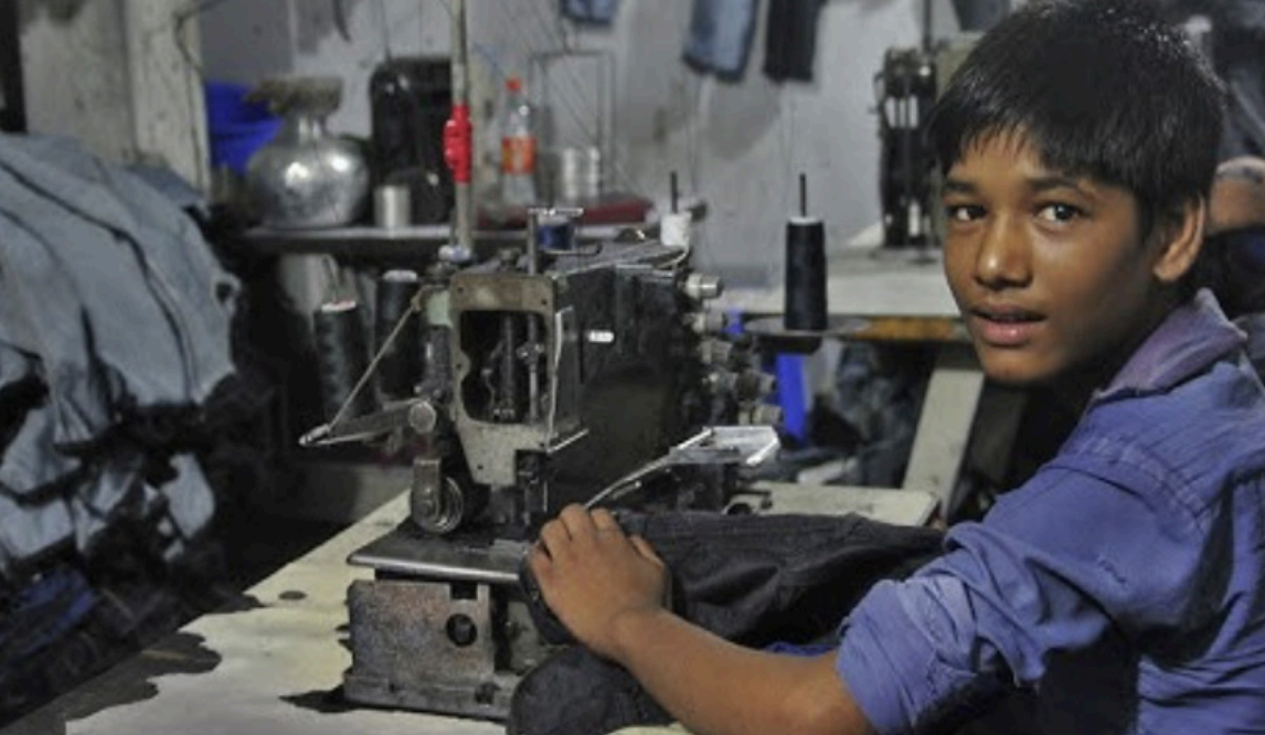 YOUNG CHILD LABORING intensively in a sweatshop